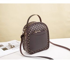 Detail view of mini vintage patterned backpack with brown leather pocket and gold zippers