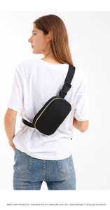 Zwarte nylon heuptas met gouden ritsen gedragen als crossbody borsttas model