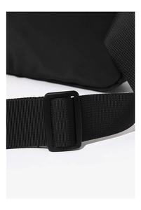 Detail van de verstelbare nylon schouderband en gesp van een zwarte crossbody borsttas
