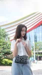 Détail de la broderie florale noire et de la bandoulière en chaîne dorée du mini sac chic