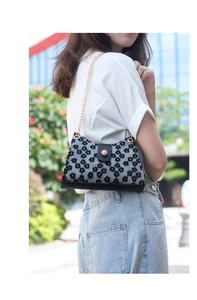 Vue détaillée du sac fleuri avec chaîne dorée porté sur un t-shirt blanc