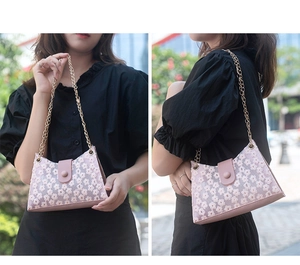 Détail du sac à fleurs en dentelle rose avec broderie marguerite et chaîne dorée