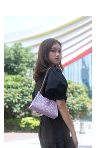 Détail du sac violet en dentelle avec broderie marguerite et bandoulière chaîne dorée