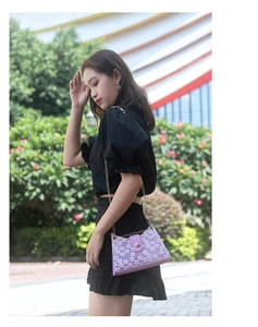 Détail d'un sac à fleurs en dentelle violette avec bandoulière en chaîne dorée et fermoir