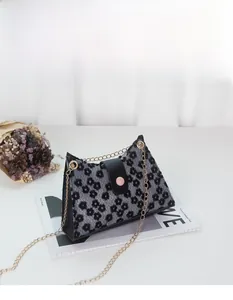 Détail d'un mini sac bandoulière triangulaire avec fleurs noires et chaîne dorée