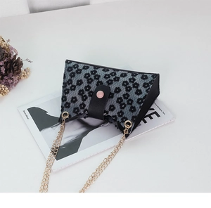 Détail du mini sac bandoulière gris avec motifs de marguerites noires et chaîne dorée