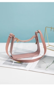 Close-up of clear PVC shoulder bag with pink leather trim and gold metal hardware