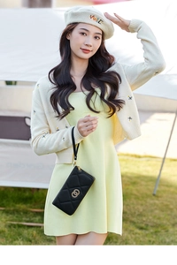 Outdoor shot of a black quilted long wallet with golden interlocking rings and wrist strap