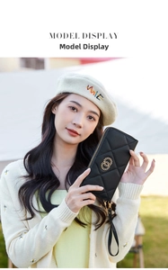 Woman holding black quilted long wallet with gold rings and wrist strap in detail