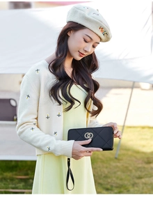 Close-up of black quilted leather long wallet with golden double ring buckle and wristlet