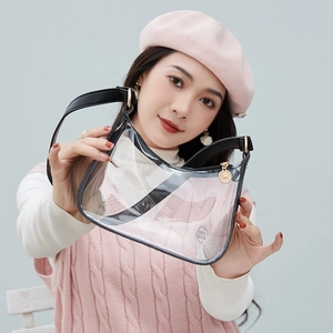 Transparent PVC half-moon shoulder bag with black trim shown on a model in soft lighting