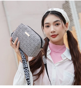Detail of checkered crossbody camera bag with gold logo and stylish printed strap