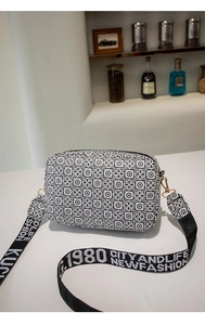 Close-up of black and white geometric print bag with wide logo jacquard strap