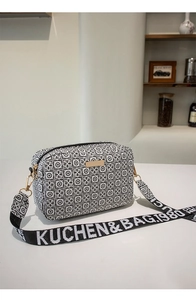 Detail of crossbody bag with black and white geometric pattern and wide woven strap
