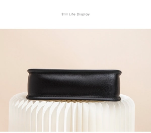 Detailed base view of black textured shell bag with reinforced edges on display stand