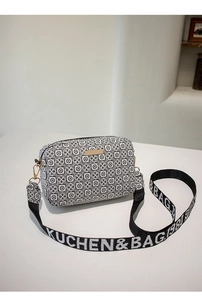 Detail of crossbody bag featuring black white geometric pattern and wide branded strap