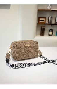 Close-up of geometric pattern crossbody bag with wide black and white lettered strap