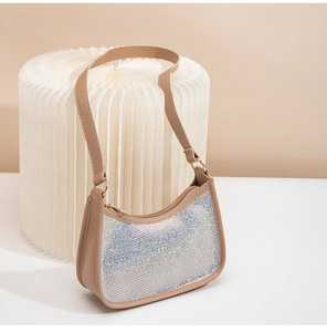 Detail of a beige shell-shaped cosmetic bag featuring iridescent rhinestones and zipper closure
