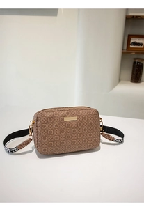 Detail of vintage patterned crossbody camera bag with stylish wide logo strap and metal plate