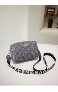 Detail of crossbody bag with black white geometric patterns and wide patterned strap