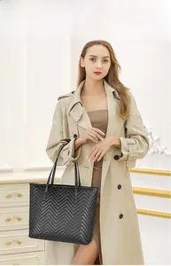 Gros plan du sac cabas matelassé noir avec surpiqûres en V sur un trench-coat beige