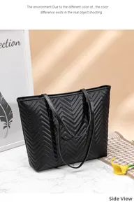 Vue latérale du grand sac cabas noir avec matelassage chevron sur une surface marbre