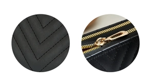 Close-up of black quilted leather texture and dual gold metal zippers on a long wallet