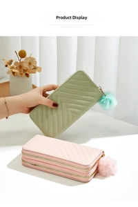 Close-up of long quilted leather wallets with fluffy pompom charms in mint and pink