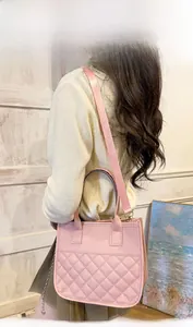 Detail view of pink quilted tote bag with wide fabric strap worn by a model