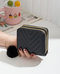 Detail of black double zipper clutch bag with V-quilted faux leather and faux fur pompom