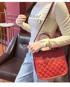 Detailed view of red quilted tote bag with elegant stitching and cylindrical handle