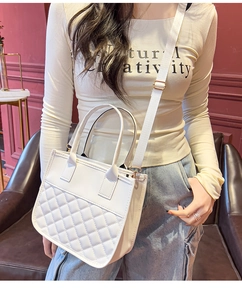 Close-up of a white quilted tote bag featuring a contrast design and gold-tone hardware