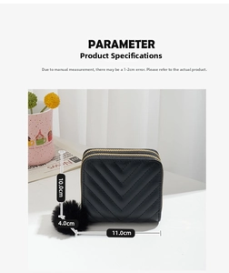 Detail view of black quilted short wallet with gold dual zippers and soft pompom charm