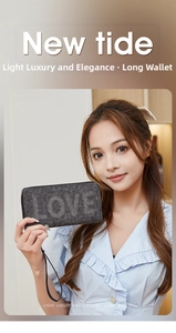 Close-up of long grey clutch wallet with sparkling LOVE rhinestone design and wrist strap