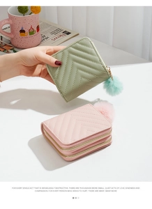 Detail of V-shaped quilted texture and gold zippers on short women's wallets with pompom charm