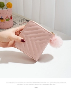 Detailed view of a pink quilted short wallet with a fluffy pompom keychain for women