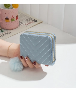 Detail of light blue quilted double-zipper wallet with a soft pompom charm accessory