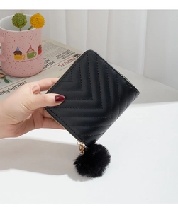 Close-up of black V-quilted wallet with gold zipper and decorative faux fur pompom