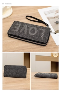 Detail of dark denim clutch bag with LOVE rhinestone letters and wrist strap on wooden desk
