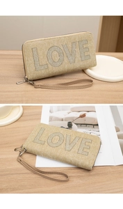 Macro shot of LOVE diamond letters on beige textured fabric wristlet wallet bag