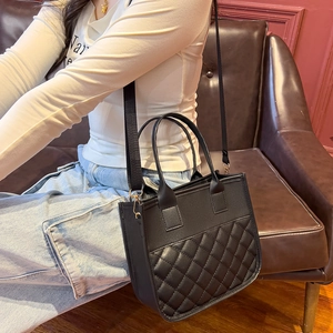 Black quilted faux leather tote bag with wide nylon strap and gold hardware