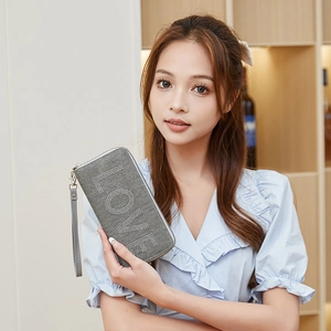 Elegante graue Clutch mit LOVE-Strasssteinen und Handschlaufe, präsentiert von einem Model