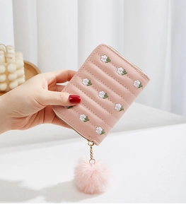 Pink short wallet with daisy embroidery, quilted texture, and a soft fur pompom charm