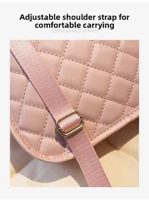 Detail of adjustable woven nylon strap and gold buckle on a quilted pink backpack