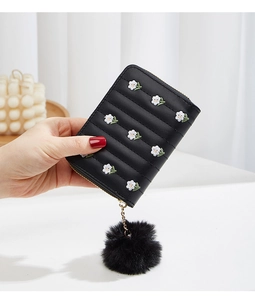 Detail of black mini coin purse with floral embroidery and fluffy pompom keychain