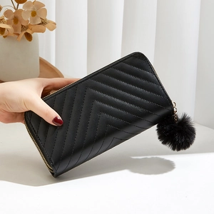Women's black long wallet with V-quilted pattern, double zippers, and fur pompom charm