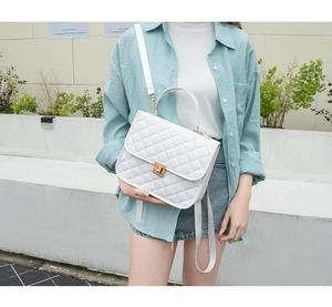 Outdoor model display of white quilted handbag with gold turn-lock and chain strap detail