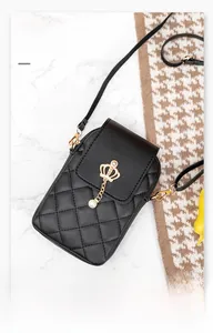 Detail of black quilted phone bag featuring a gold crown emblem and elegant pearl charm