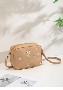 Detailed close-up of floral embroidery and 3D butterfly on a beige crossbody phone bag