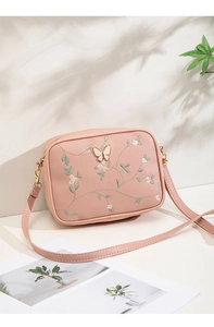 Detail of pink floral camera bag with delicate embroidery and metal butterfly decor